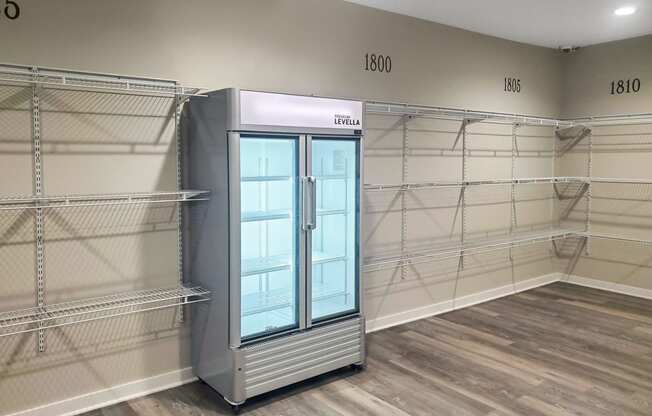 a large walk in closet with a refrigerator and shelves