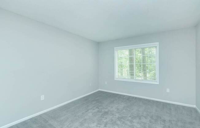 A room with a window and a grey floor.