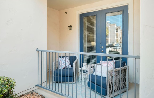 A balcony with a blue chair and a white pillow.