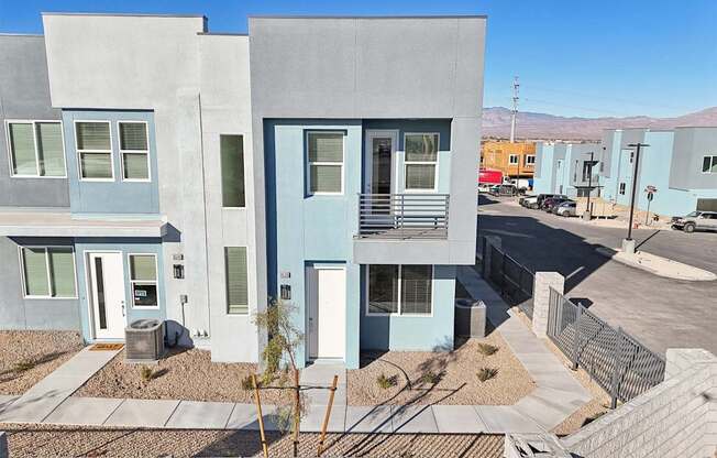 A modern two story house with a blue door and window.