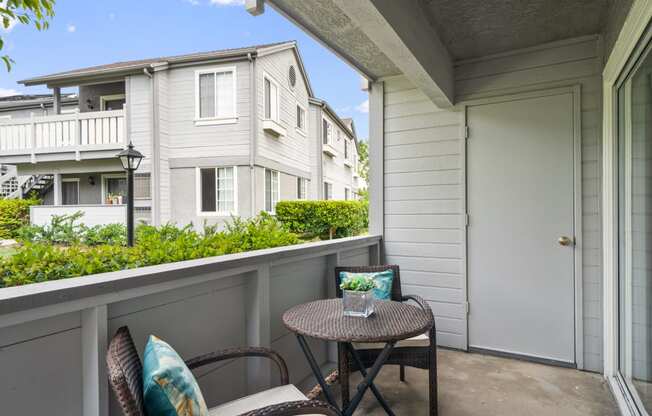 a patio with two chairs and a small table on a balcony