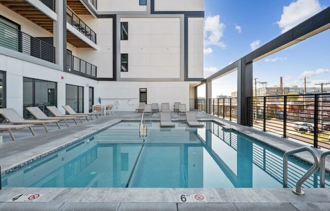 a swimming pool with lounge chairs and a building in the background at The Box, Virginia, 23224