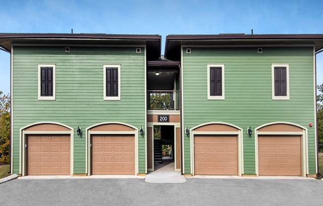 a green building with brown garage doors