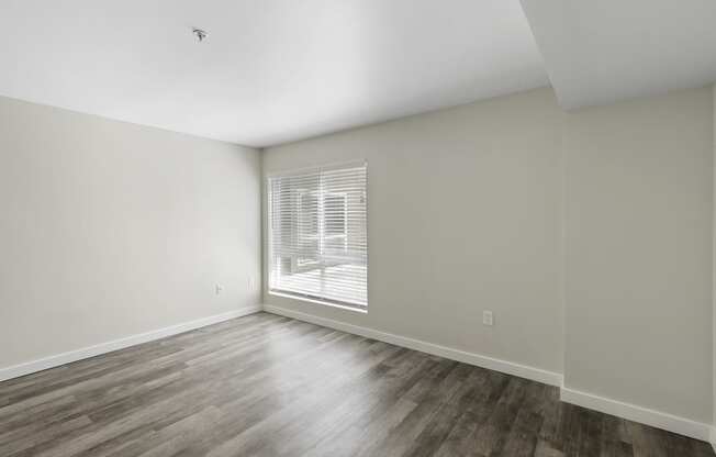 a bedroom with hardwood flooring and a large window at Excalibur Apartment Homes, Bellevue, Washington 98004