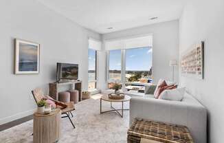 A living room with a grey couch, a wooden table, and a painting on the wall.