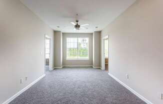A spacious room with a ceiling fan and carpeted floor.