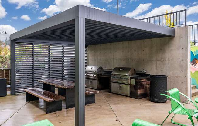 a covered patio with two bbqs and a picnic table