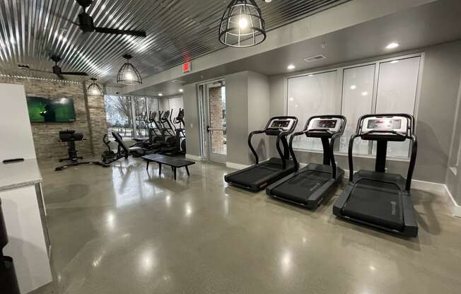 a gym with treadmills and other exercise equipment in a building with glass doors at Edge 35, Indianapolis