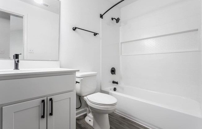 A white bathroom with a toilet, sink, and bathtub.