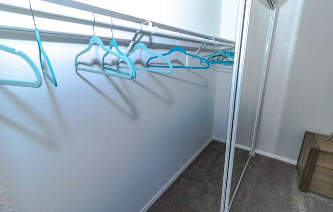 a walk in closet with a mirrored wall and blue hangers