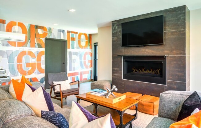 Resident lounge at our apartments for rent in Washington DC, featuring a fireplace, a TV, and colorful wall paper.