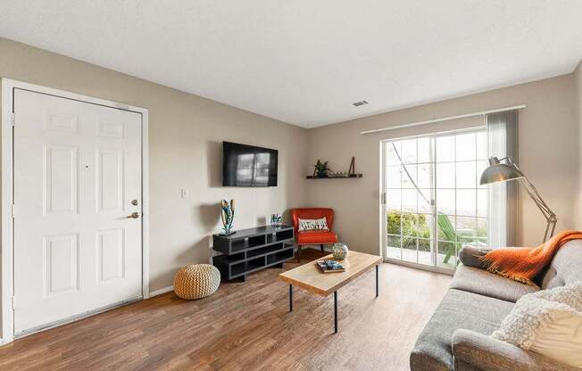A living room with a grey couch, a wooden coffee table, and a white door.