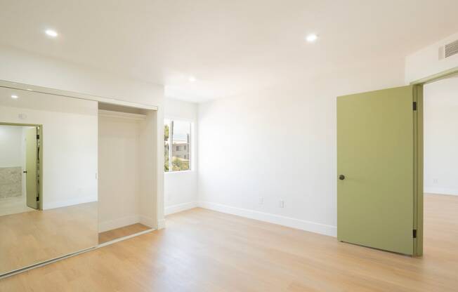 a living room with white walls and a green door