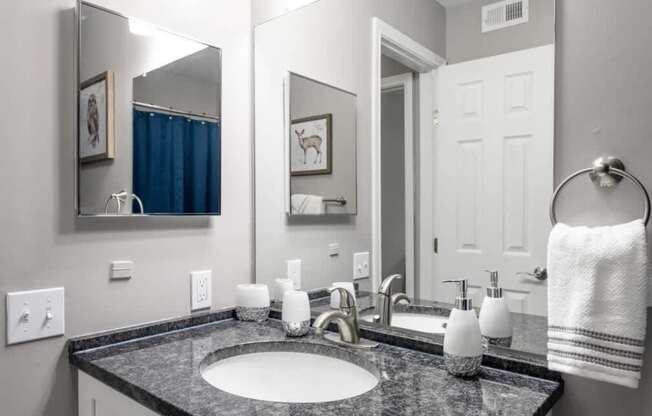 A bathroom with a sink, mirror, and towel.