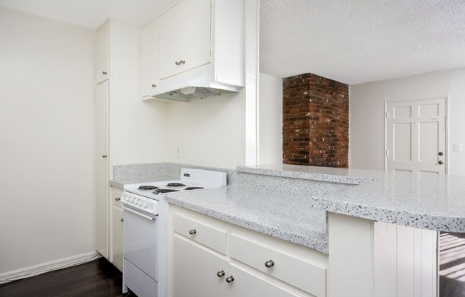 an empty kitchen with white appliances and granite counter tops