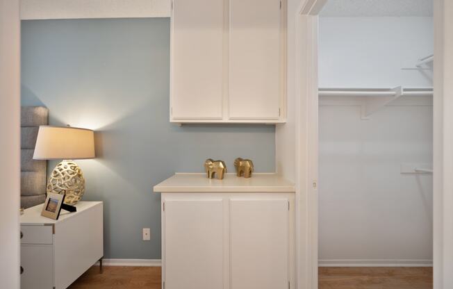 a living room with white cabinets and a desk with two gold elephants