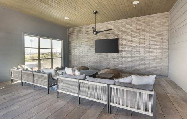 a living room with a couch and a tv on a brick wall