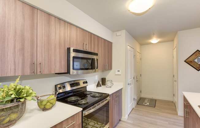 Kitchen with Countertop,MMicrowave, Wood Inspired Floor, Oven, Wood Cabinets, Ceiling Lights, Fruit Bowl