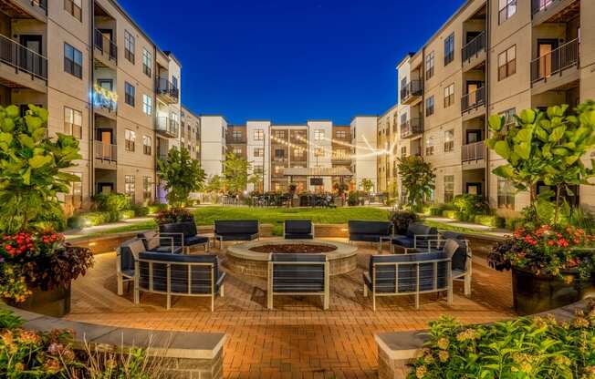 an outdoor area with a fire pit and chairs in front of an apartment building