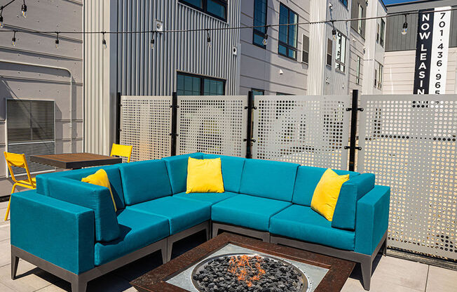 a patio with a blue couch and yellow pillows at The Landing at 1001 NP, Fargo, ND 58102