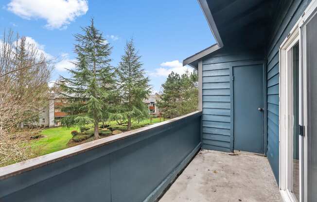 A balcony with a view of trees and a house.