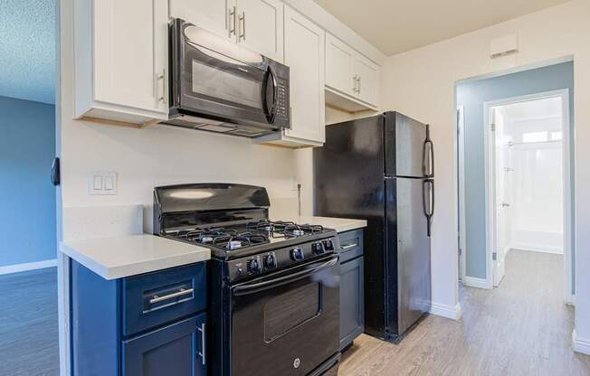 A kitchen with black appliances and white cabinets.