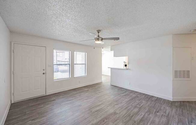 A room with a ceiling fan and wooden flooring.