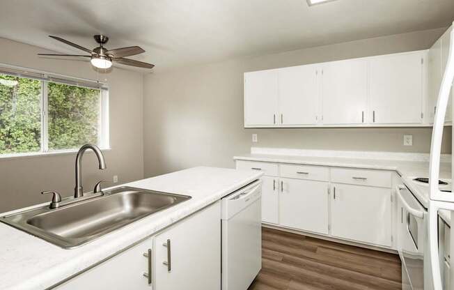 A kitchen with white cabinets and a stainless steel sink.