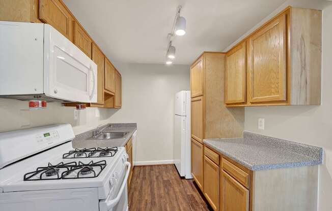 A kitchen with white appliances and wooden cabinets.