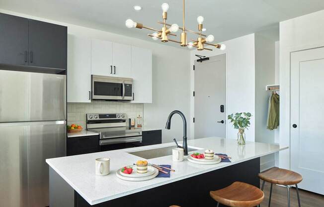 A modern kitchen with a white countertop and black cabinets.