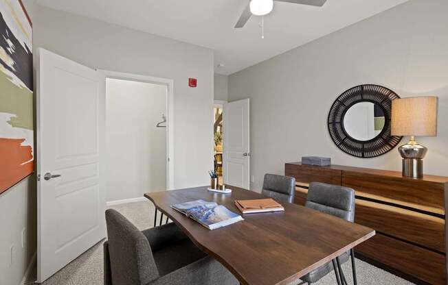 Flatiron West Trade Apartments staged model unit home office with gray carpet and dark wood furniture