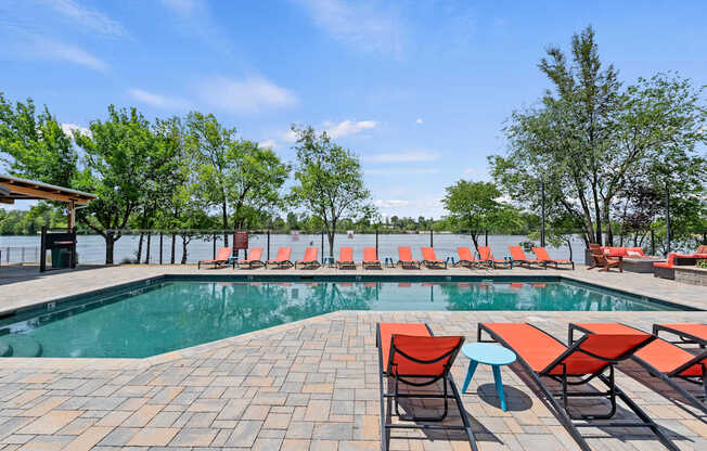 A pool area with red chairs and a clear blue sky.