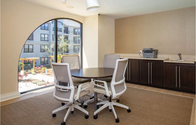 Round table with 4 computer desk chairs and printer located on top of counter. Located on the 2nd floor of Clubhouse.