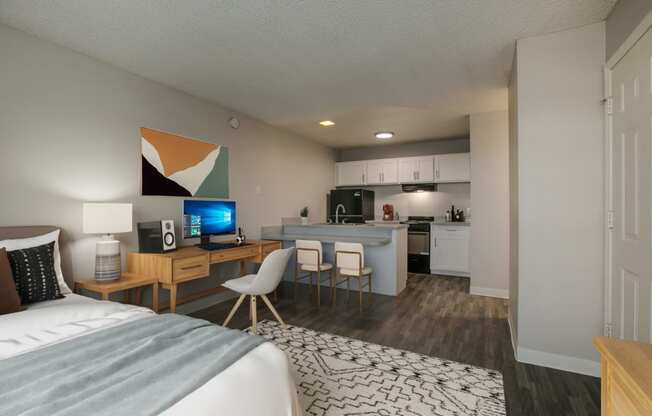 a bedroom with a bed and a desk and a kitchen