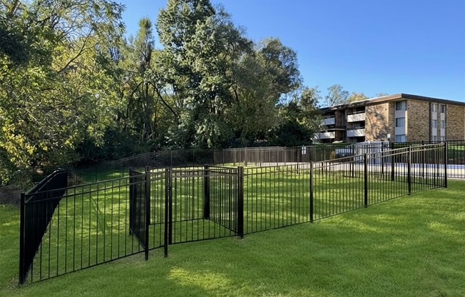 A black metal fence surrounds a green lawn.