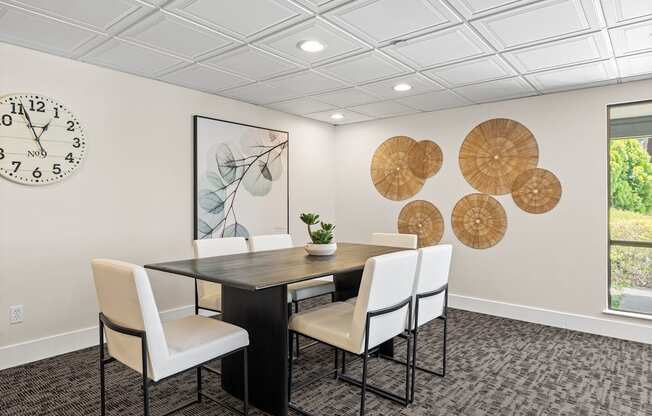 A dining room with a table, chairs and a clock on the wall.