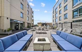 a seating area with couches and chairs on a patio with a fire pit in the middle at Lakeview 3200 Apartments, Chicago, IL