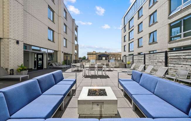 a seating area with couches and chairs on a patio with a fire pit in the middle at Lakeview 3200 Apartments, Chicago, IL