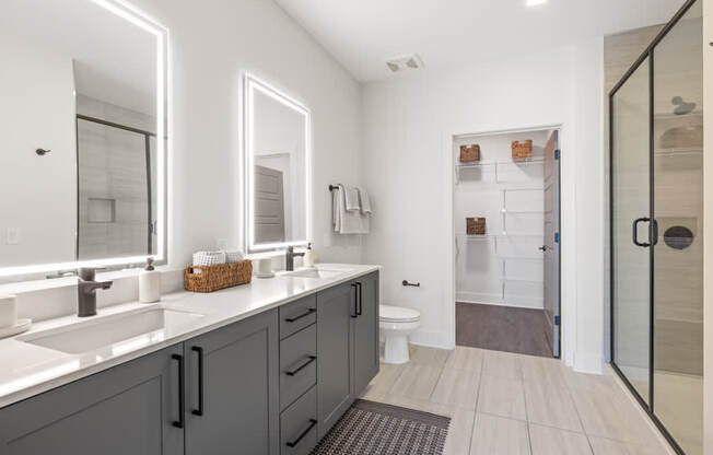 A bathroom with a white sink and grey cabinets.
