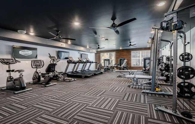 A gym with a variety of equipment including treadmills, weights, and exercise machines.