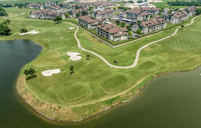 an aerial view of a golf course next to a body of water and a city