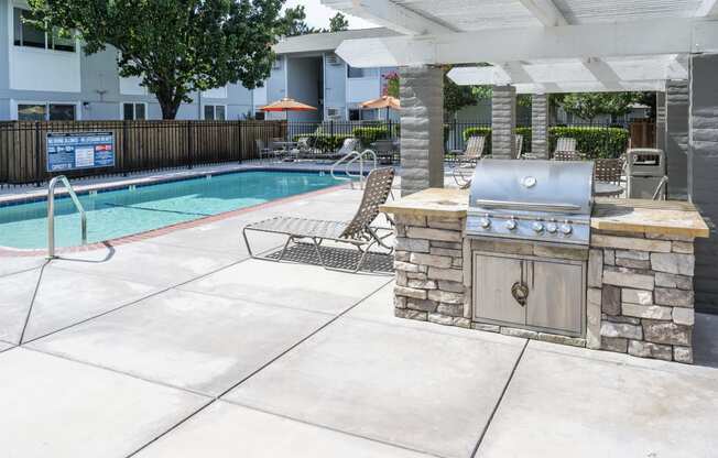 a patio with a grill next to a swimming pool