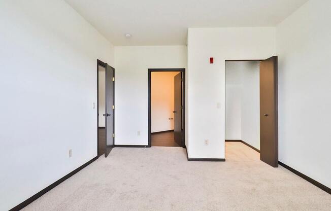 A white room with a carpet floor and three doors.
