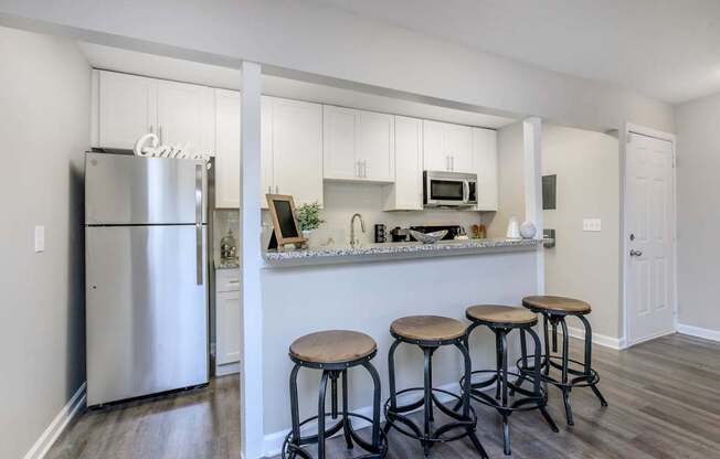 A kitchen with white cabinets and a stainless steel refrigerator.