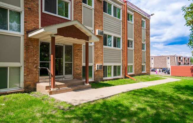 a brick building with a porch and a sidewalk in front of it