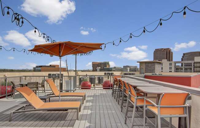 a rooftop deck with orange lounge chairs and umbrellas