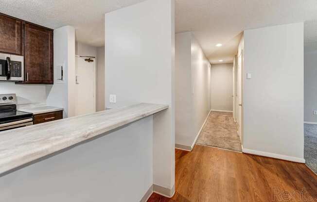 a kitchen with a counter and a hallway to a living room