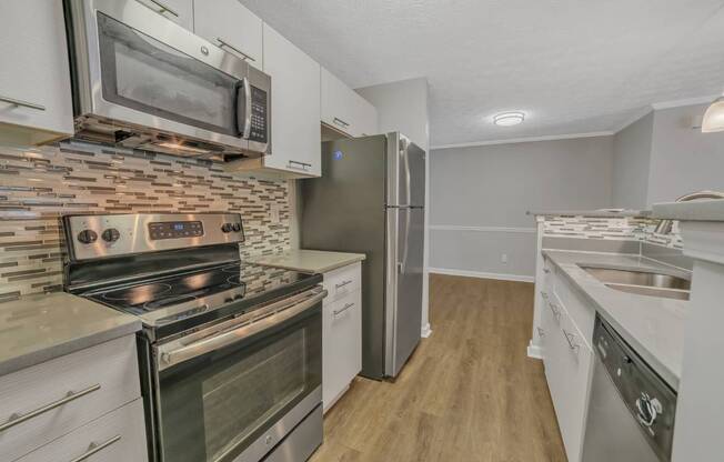 A kitchen with a stove, oven, refrigerator, and microwave.