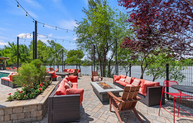 A patio with red cushions and wooden chairs overlooks a body of water.