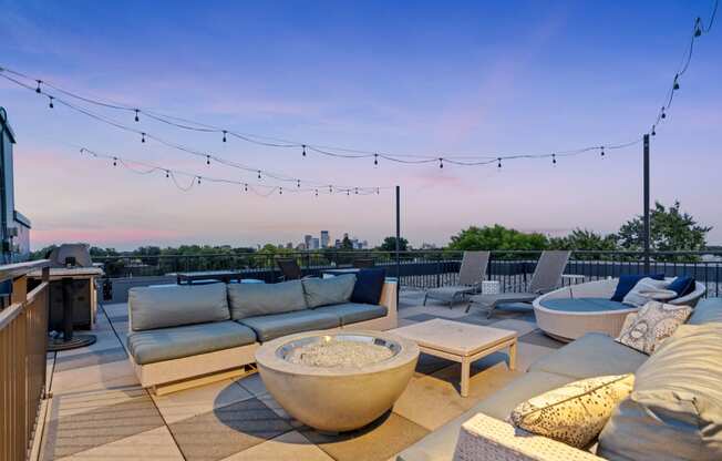 a roof deck with couches and chairs and a fire pit